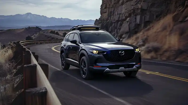 A photo of a 2024 Mazda CX-90 driving through a scenic mountain road.