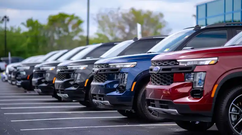 A row of unsold 2023 SUVs parked in a dealership lot.