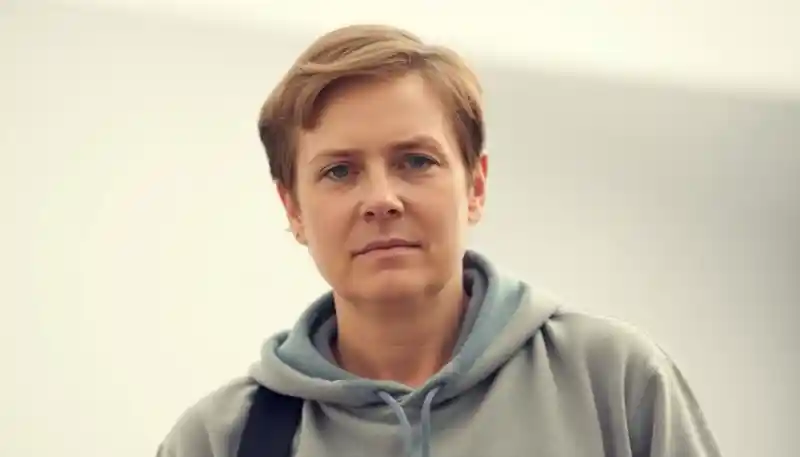 a woman with short hair wearing a grey sweatshirt